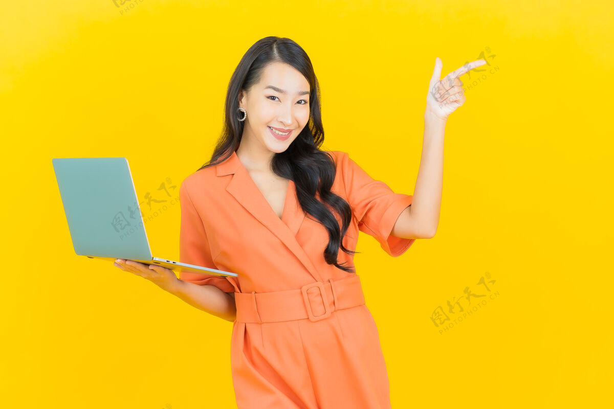 肖像肖像美丽的亚洲年轻女子微笑着用黄色笔记本电脑人员年轻人成人