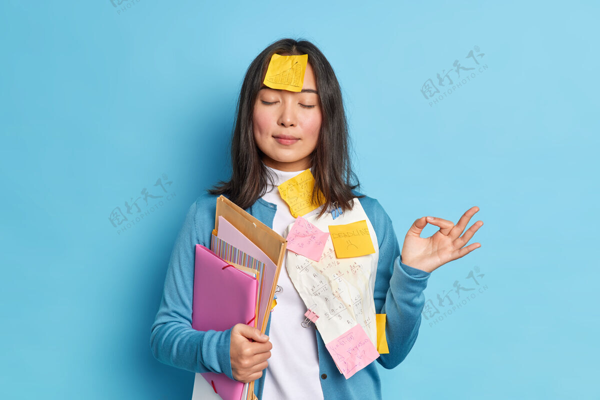 累了放松的学生的画像试图放松冥想室内使好的手势保持眼睛闭上拿着文件夹粘在纸上女人放松卡住