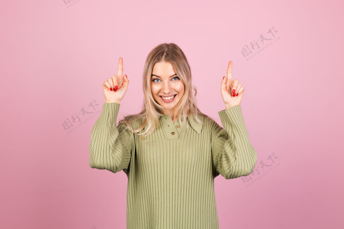衣服漂亮的欧洲女人在粉红色的墙上穿着休闲针织毛衣女性思考姿势