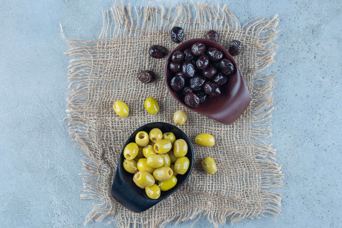 油两碗绿黑橄榄放在大理石表面碗小吃健康