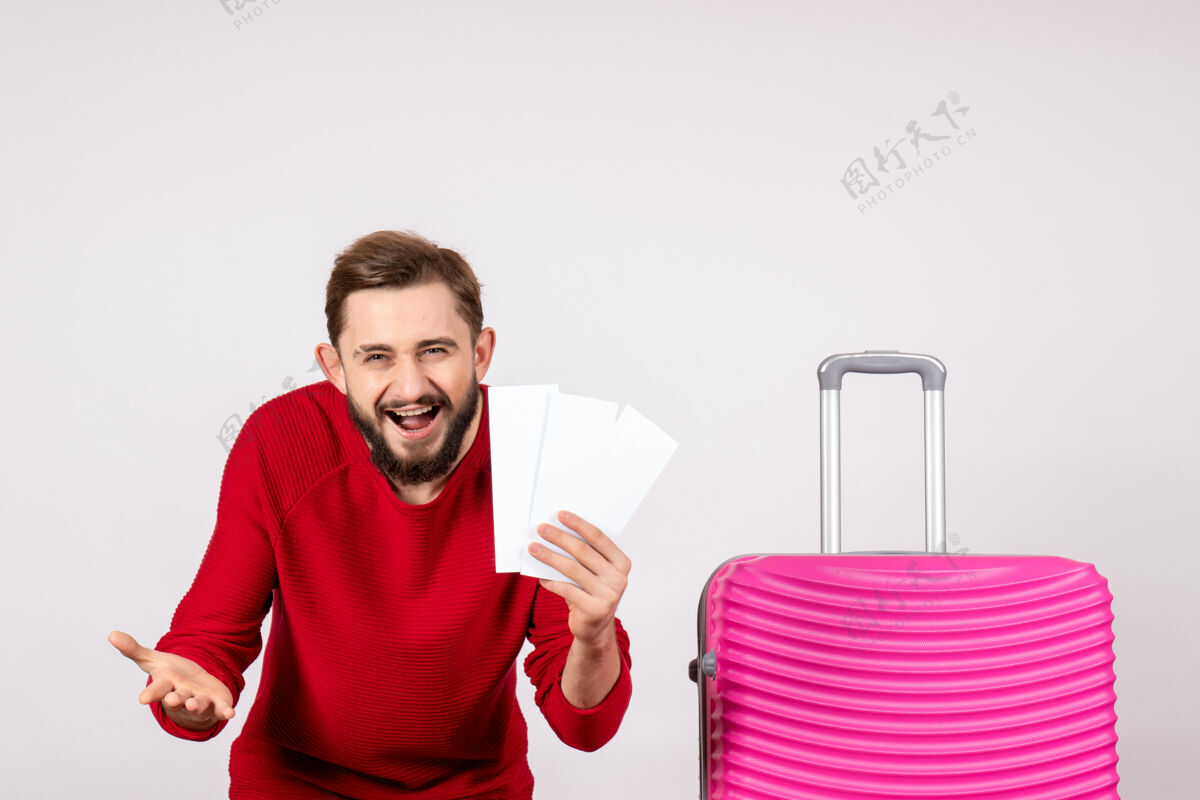 航班正面图：年轻男性 带着粉色的包 拿着白墙上的机票 远航航班 彩色旅行 旅游度假情感情绪男人风景