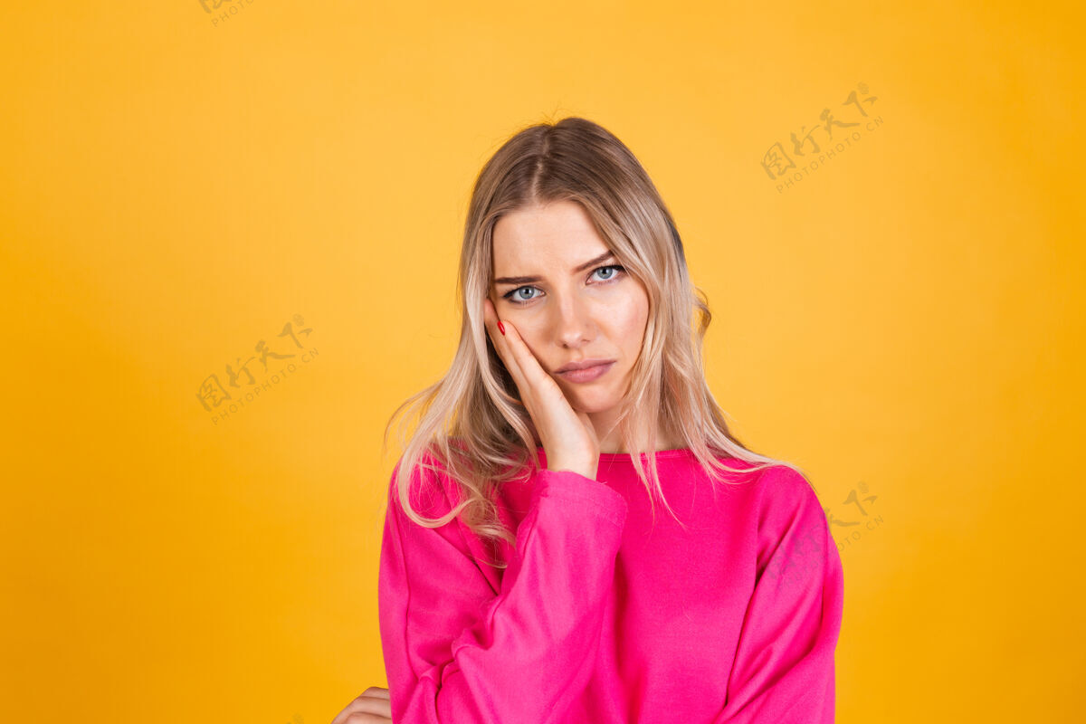 肖像黄色墙上穿粉红色上衣的漂亮欧洲女人人站立烦恼