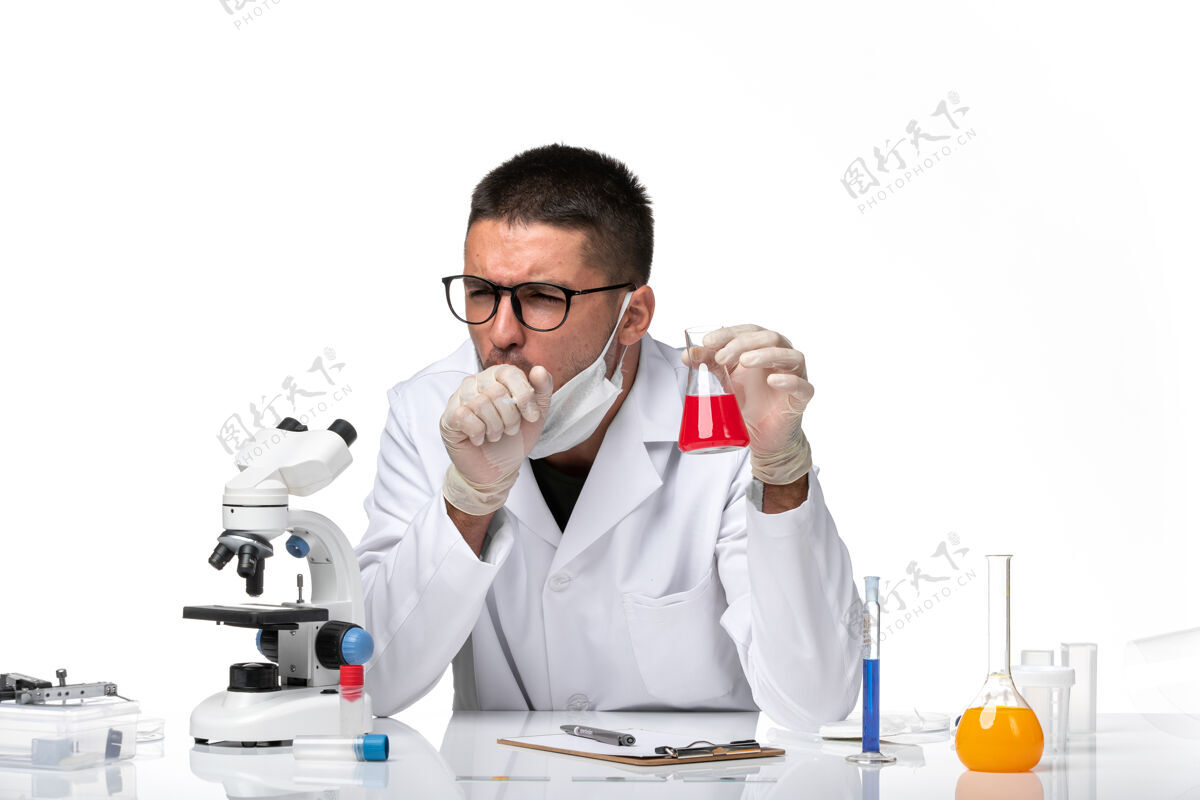 视图正面图：男医生穿着白色医疗服 戴着面罩 在白色空间里放着红色溶液实验室外套溶液诊所