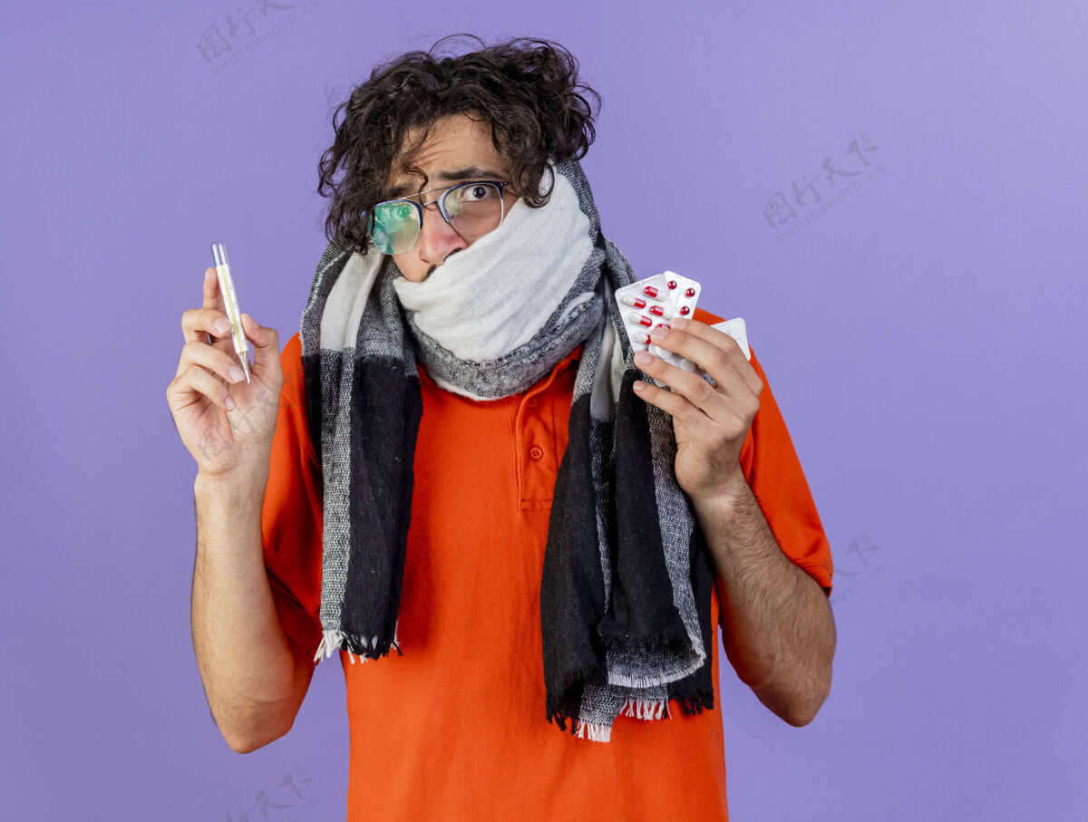 围巾焦急的年轻病人戴着眼镜 戴着围巾 拿着药片和体温计 看着前面隔离着的紫色墙壁 留着复印空间感觉表情药丸