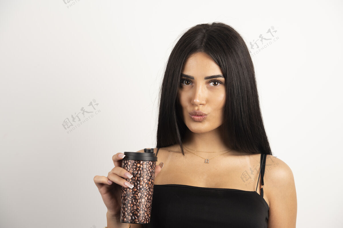 肖像一位身穿黑色上衣的女士拿着一杯咖啡 背景是米色的高质量的照片咖啡女孩热