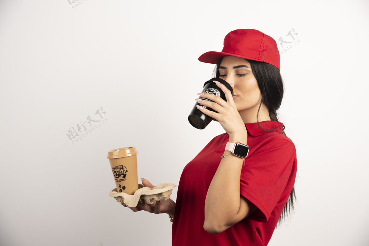 制服漂亮的信使喝着新鲜的咖啡高品质的照片工人饮用展位