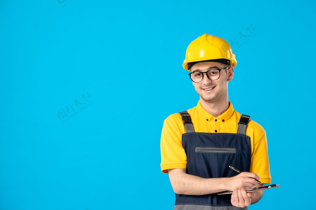 工人正面图穿黄色制服的男工人在蓝色上做笔记勤杂工男人建筑