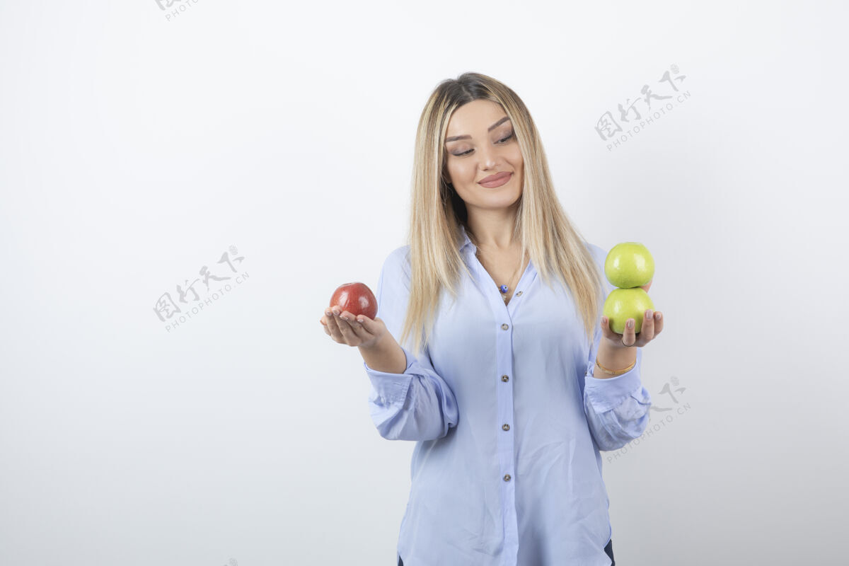 姿势一个美丽迷人的女模特站着拿着新鲜苹果的肖像照人人新鲜