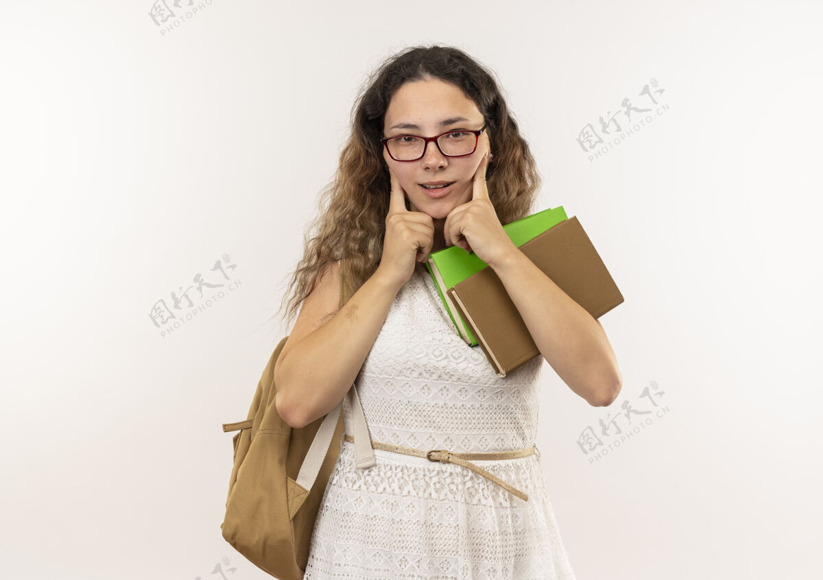 印象印象深刻的年轻漂亮的女学生戴着眼镜背着书包看着前面把手指放在脸上孤立的白色年轻女生眼镜