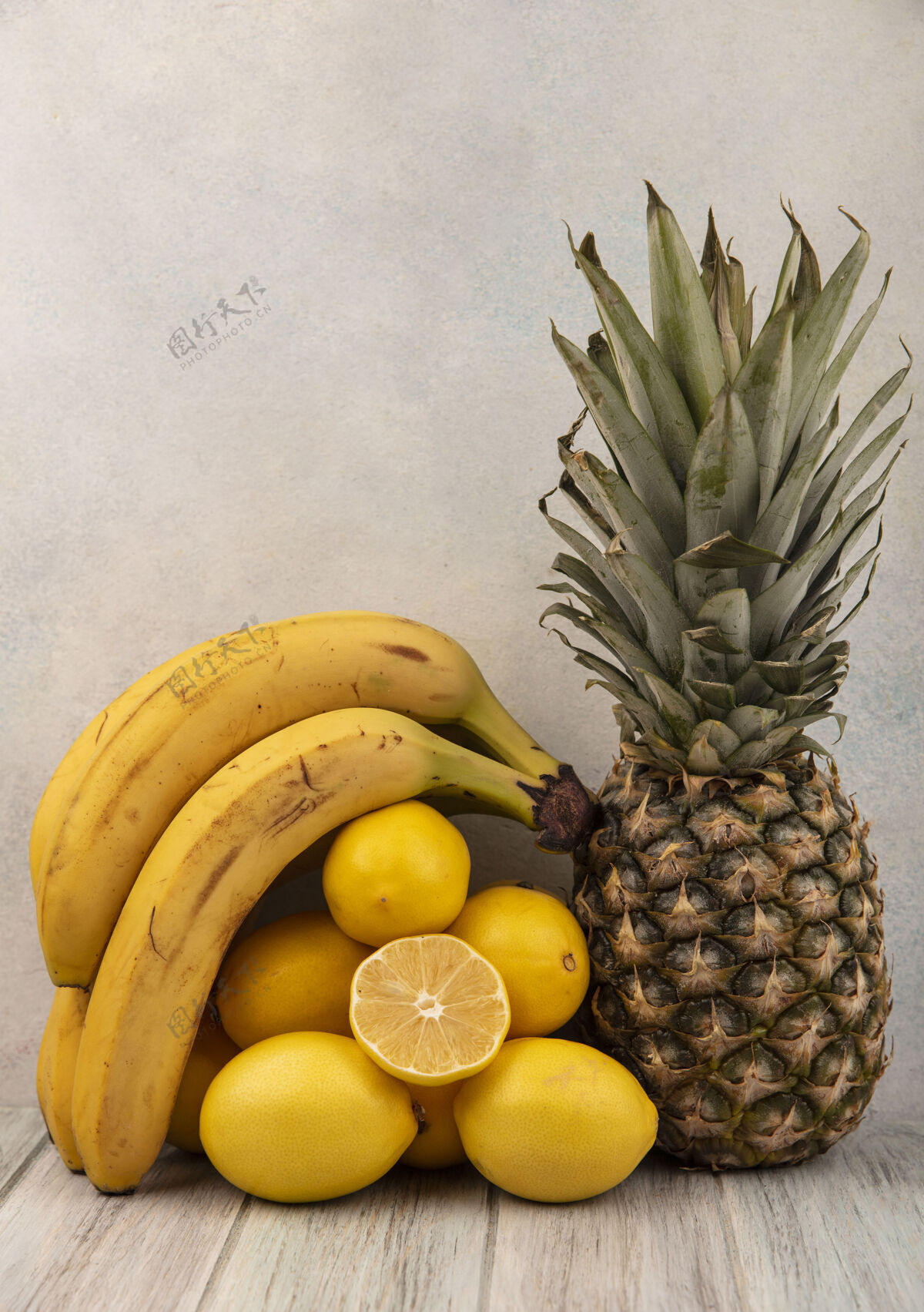 木材侧视图新鲜可口的水果 如香蕉柠檬和菠萝隔离在一个灰色的木制桌子上的白色背景白色香蕉新鲜
