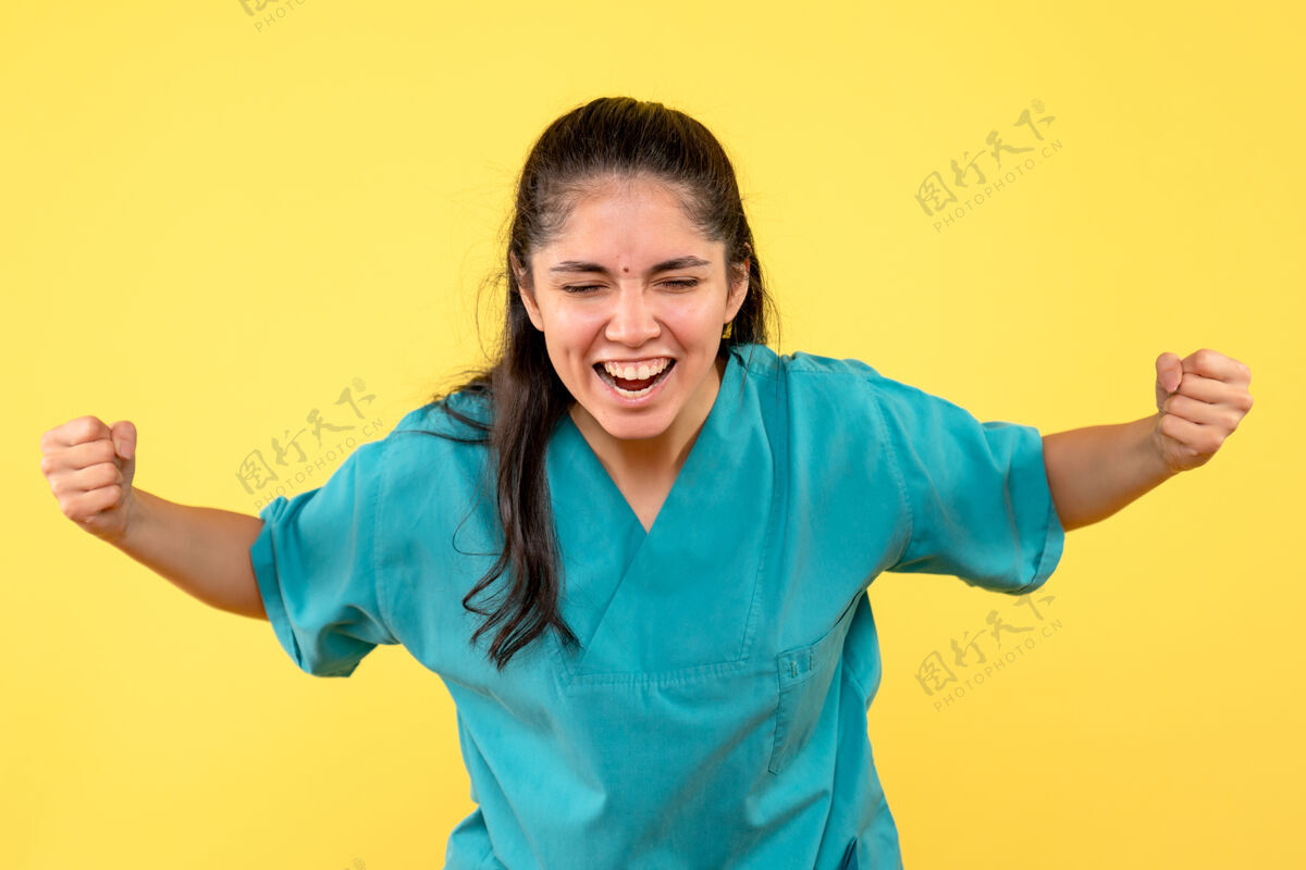 成人正面图身着制服的女医生展示胜利姿态微笑黄色肖像