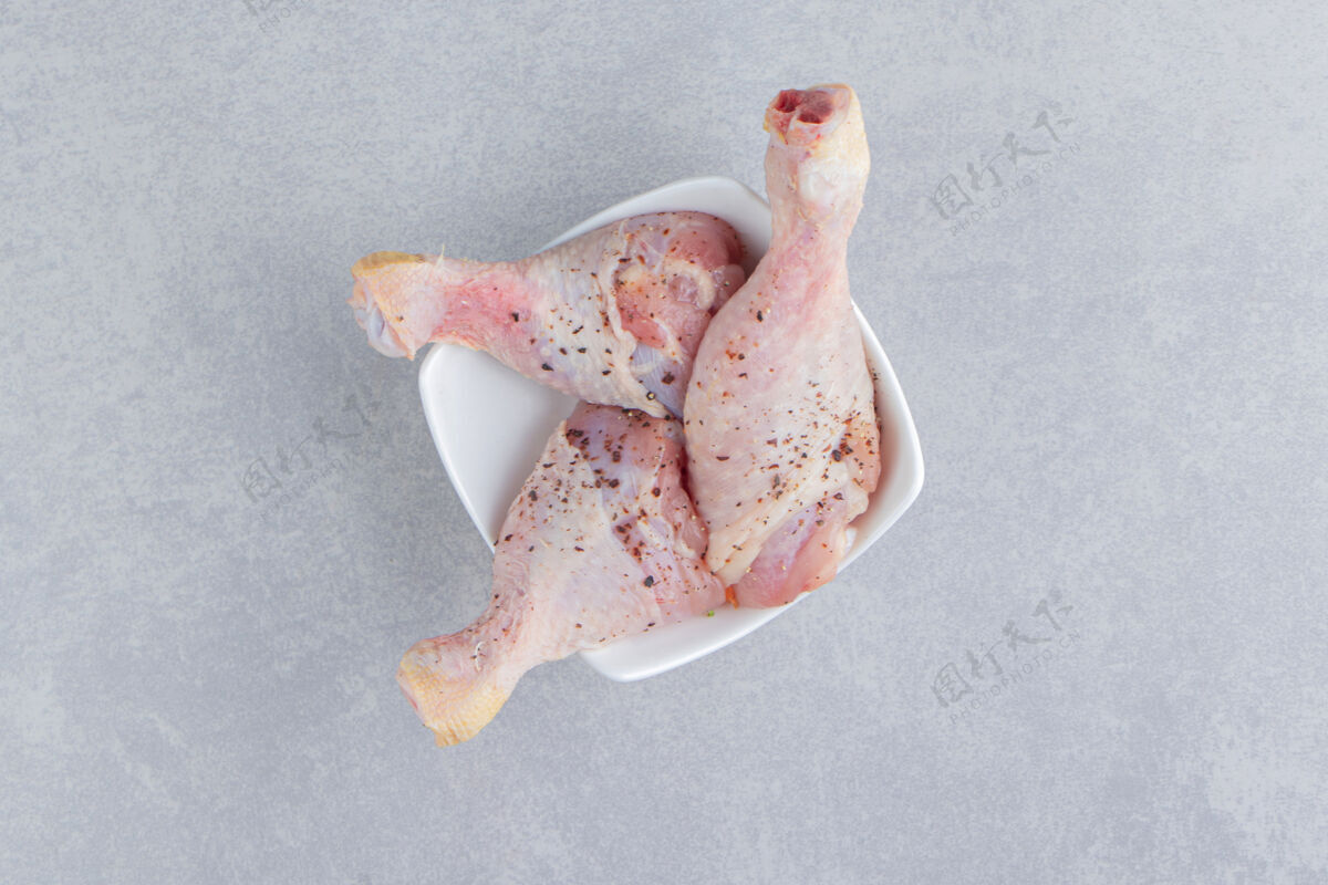美味新鲜的鸡腿在碗里 在蓝色的表面上鸡腿生的肉