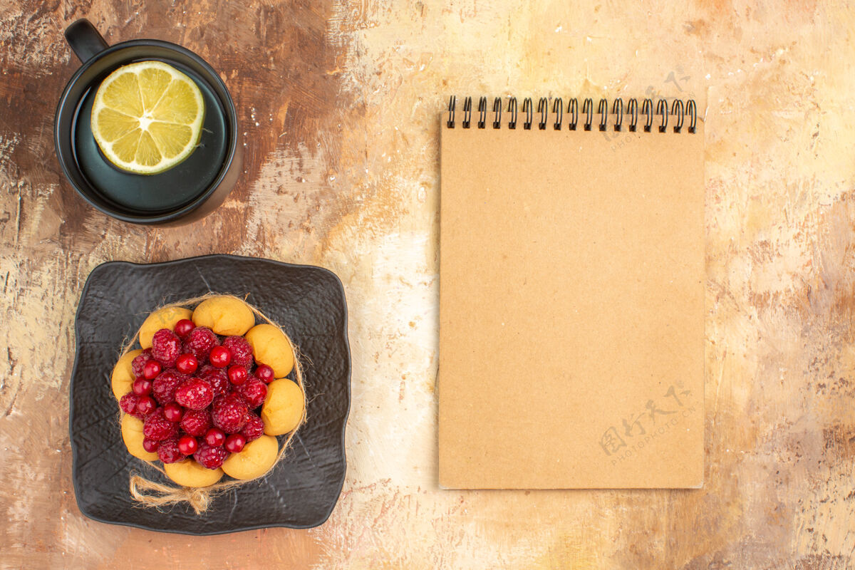 碗一个带有覆盆子的礼品蛋糕和一杯柠檬茶以及笔记本的水平视图食物营养水平