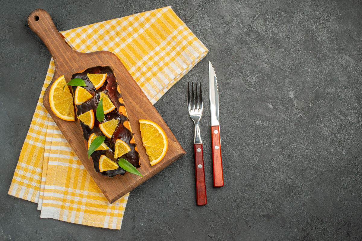 盒子上图：美味的松软的蛋糕放在木板上 切橘子的叶子放在深色的桌子上切割深色木板