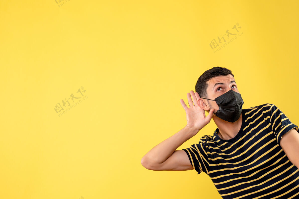 一正面图帅哥戴着黑色面具 听着黄色孤立的背景面具成人表情