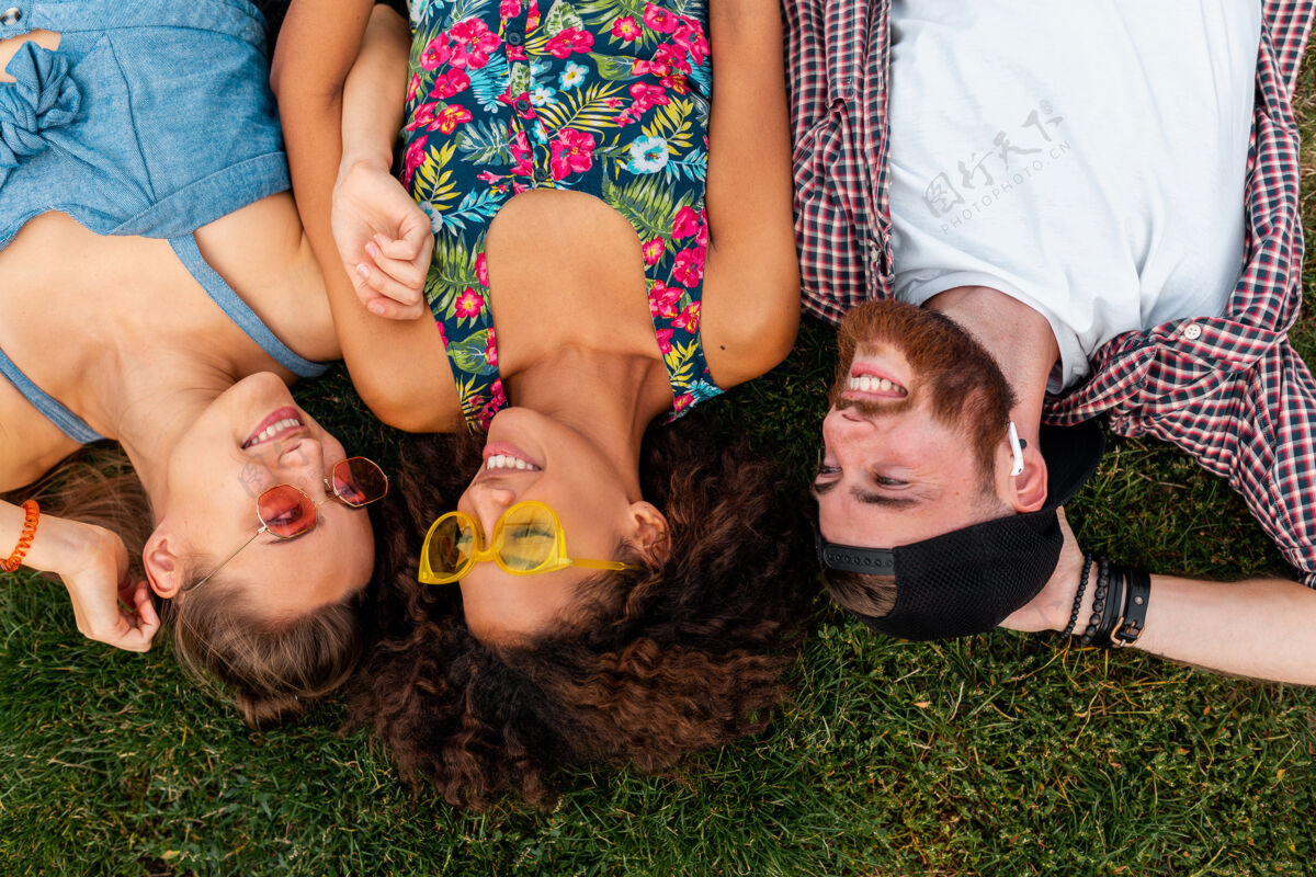 多样性俯瞰五颜六色时尚快乐的年轻朋友们躺在公园的草地上 男女同乐兴奋微笑女人