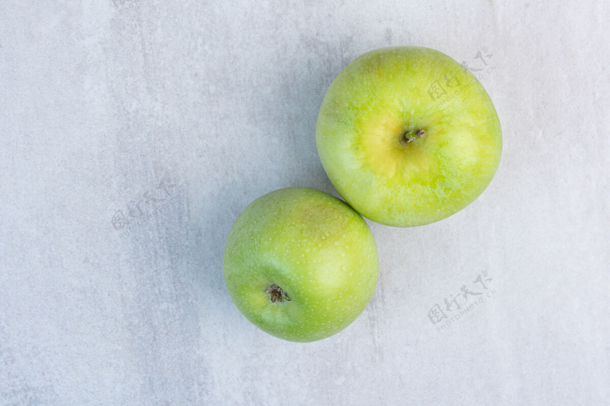 美味两个新鲜的绿色苹果 放在大理石上美味健康成熟