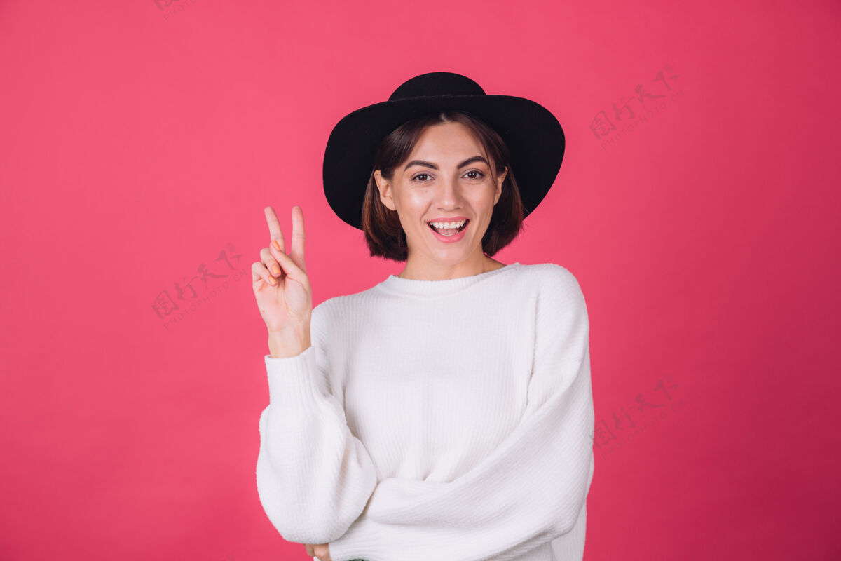 积极穿着白色休闲毛衣 戴着红粉色帽子的时髦女人快乐赢家享受