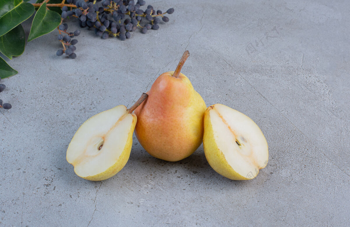 美味在大理石背景上的装饰性树枝旁切一整块梨美味整体水果