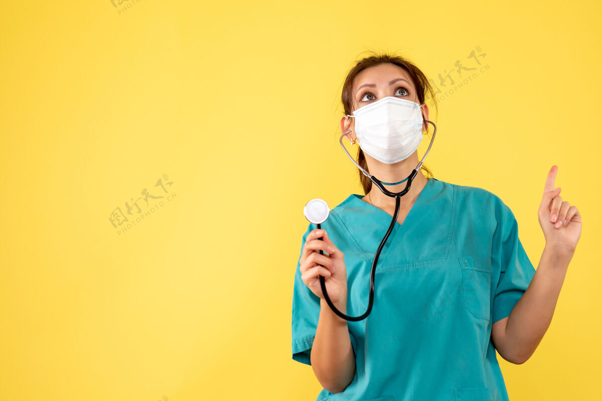 面罩正面图黄色背景上穿着医用衬衫和带听诊器面罩的女医生病毒大流行医疗