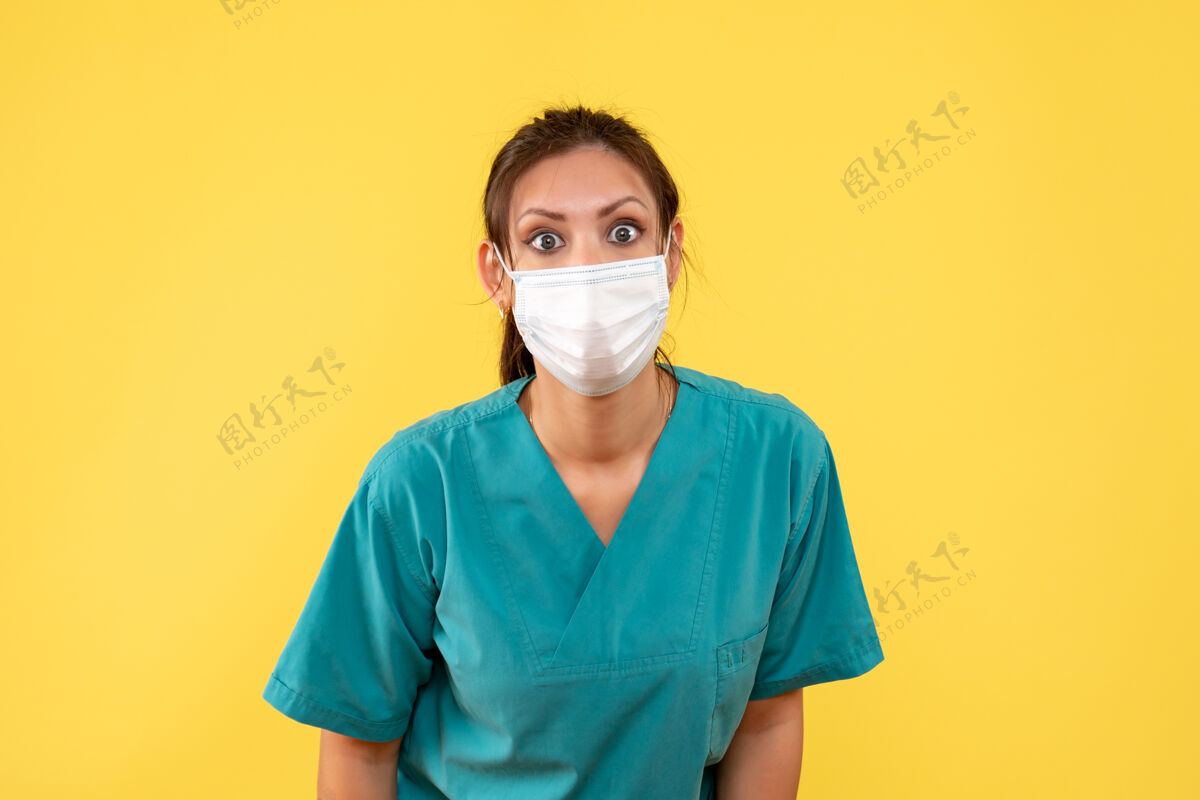 专业前视图黄色背景上穿着医用衬衫和面罩的女医生医疗面具衬衫