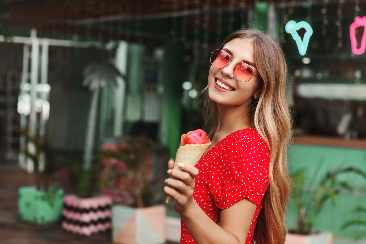 街头美丽的时髦女孩戴着太阳镜 一边吃着冰淇淋 一边微笑太阳镜梦幻乐趣