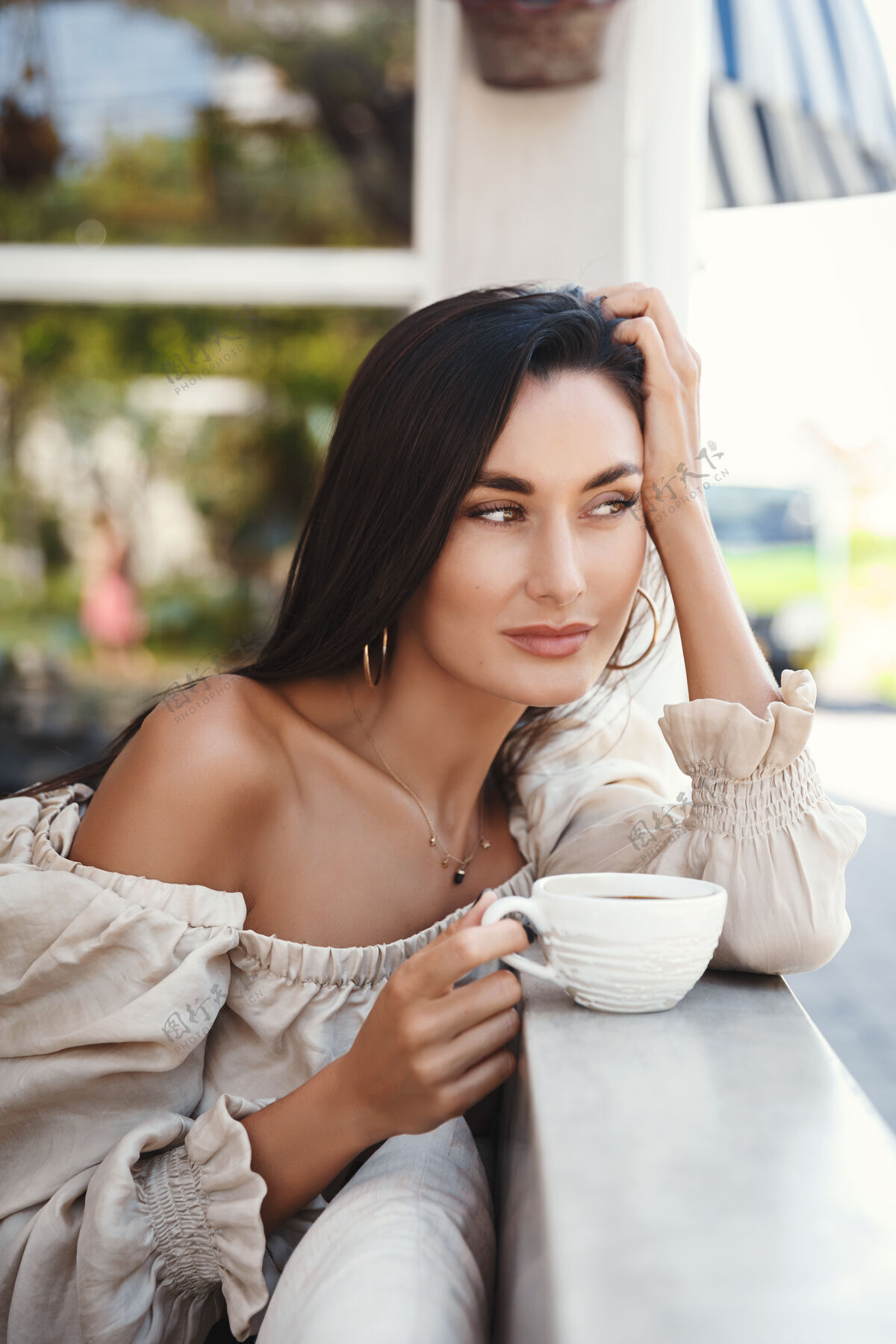 休闲垂直拍摄的是一位金发碧眼的美女 坐在咖啡馆里喝着一杯咖啡 望着街道女性化阳光午餐
