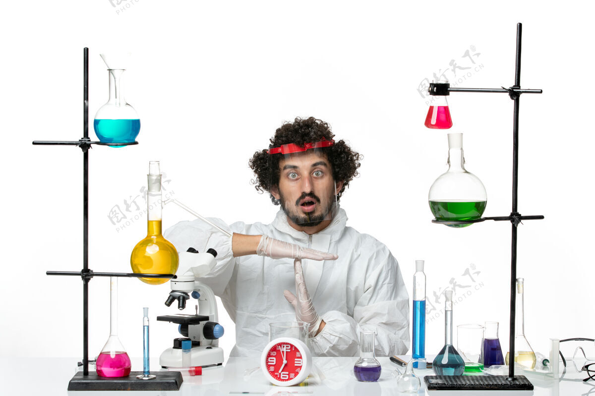 化学正面图身穿特殊套装 戴着白色防护头盔的年轻男性科学家磨损瓶子化学