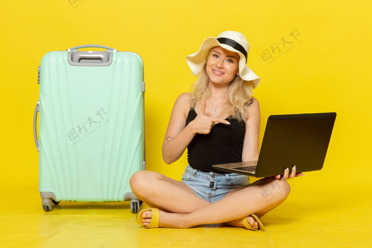 视图正面图年轻女性用笔记本电脑上的黄墙女孩远航度假旅行太阳微笑成人年轻