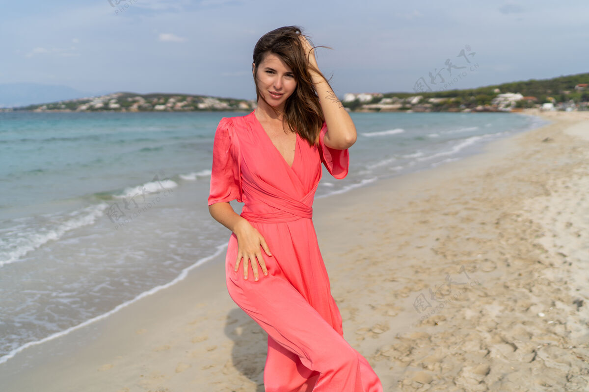 自由性感的黑发女人手上拿着塔图 穿着粉色连衣裙在海滩上摆姿势快乐女人女性