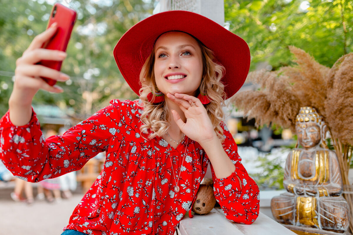 配件迷人的时尚金发微笑的女人在稻草红色帽子和衬衫夏季时尚服装拍照自拍智能手机咖啡厅相机手机街道