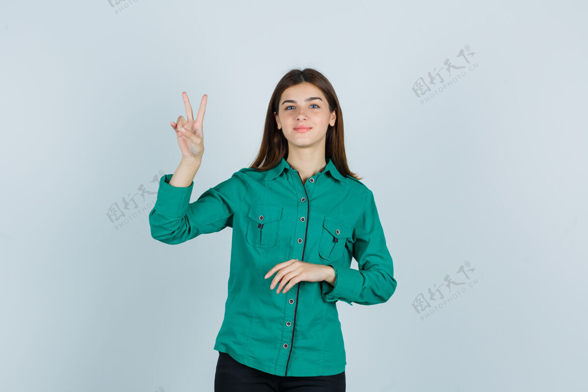 乐趣身着绿色衬衫的年轻女士展示着胜利的姿态 看上去很高兴 正对着前方时尚头发姿势