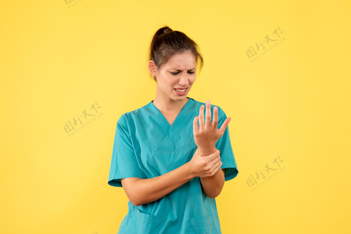 肖像前视图穿着医用衬衫的女医生在黄色背景上伤了胳膊女医生手臂受伤