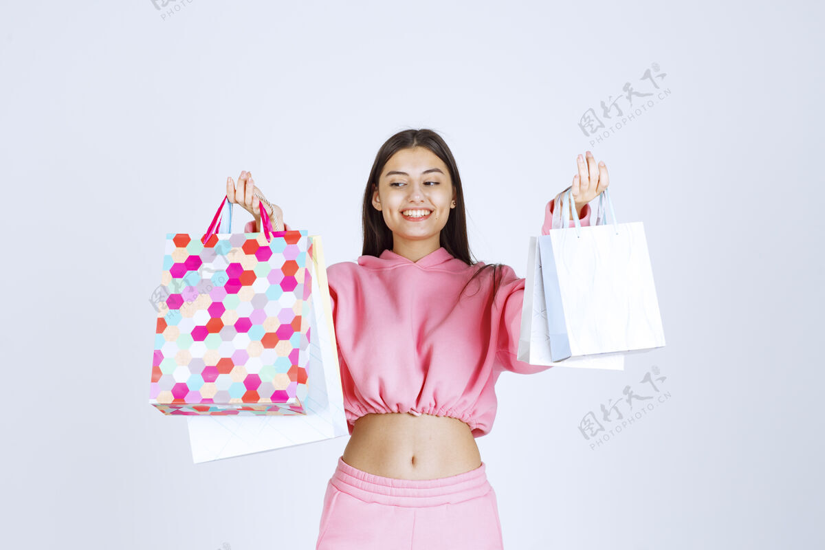 女性带着五颜六色购物袋的女孩看起来很开心很满意积极人体模特人类