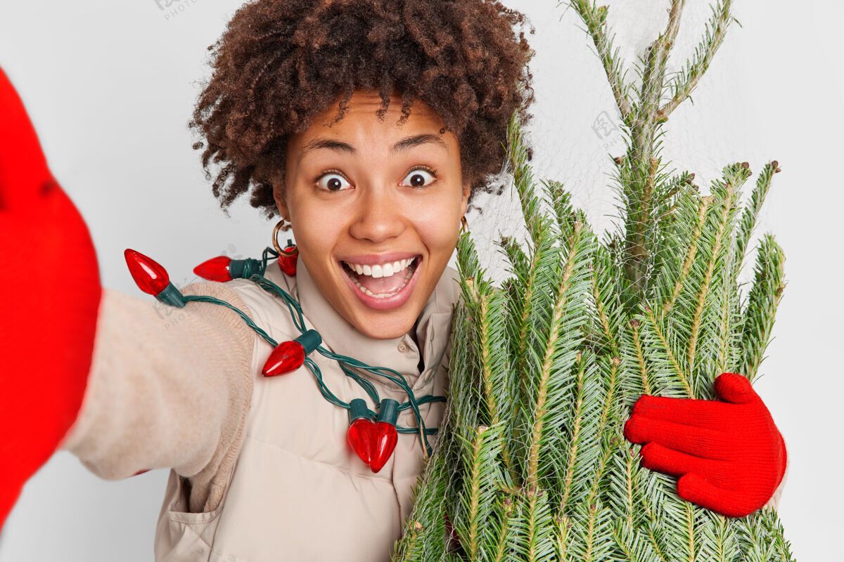 非洲过度运动积极卷曲的女人伸展手臂自拍笑容满面买了新剪的常绿杉树准备过年圣诞节快到了节日人圣诞节