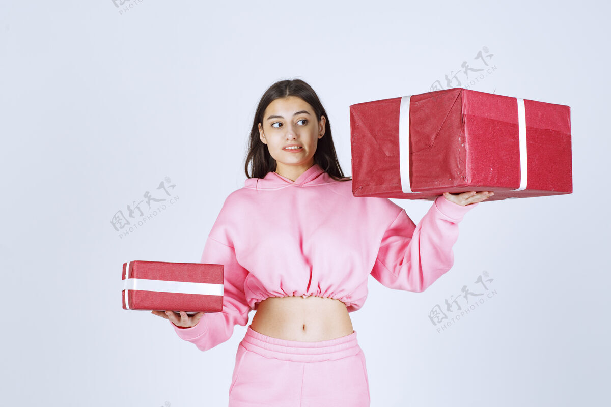 职员穿着粉色睡衣的女孩拿着大大小小的红色礼盒 看上去很不满意恐惧成人照片