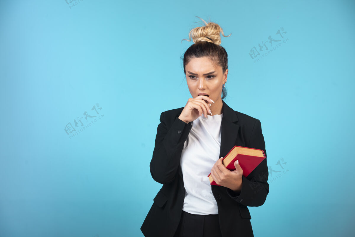 任务穿着黑色西装的年轻女商人手里拿着一本书在思考工作工资面试