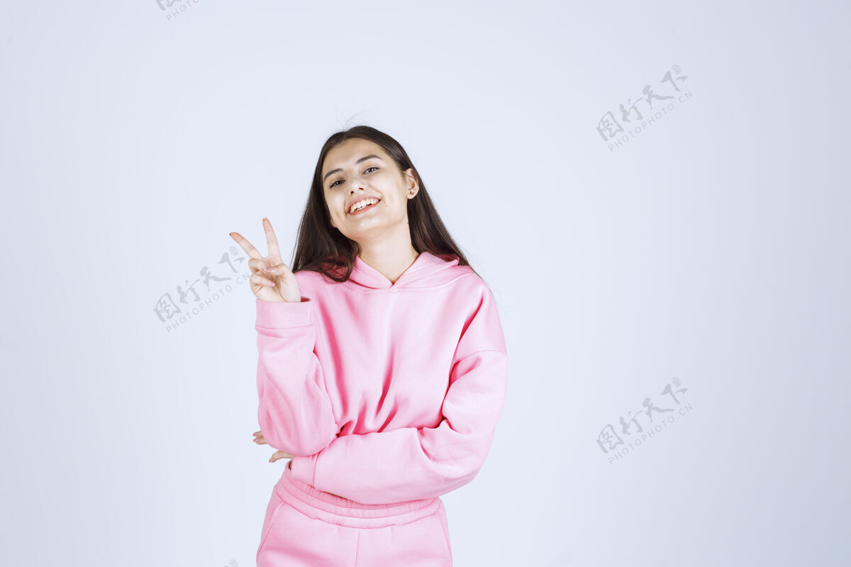 员工穿粉红色睡衣的女孩感到高兴 并显示积极的手势成人女性人体模特