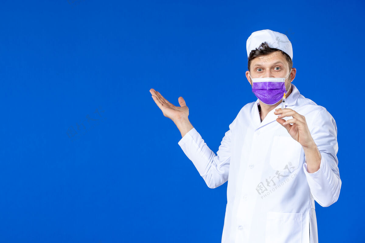 大流行前视图中的男医生穿着医疗服和面具举行注射蓝色治疗男医生注射