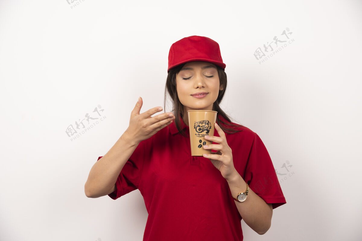 帽子穿着红色制服的女人在咖啡杯里嗅着咖啡的香味制服模特女士