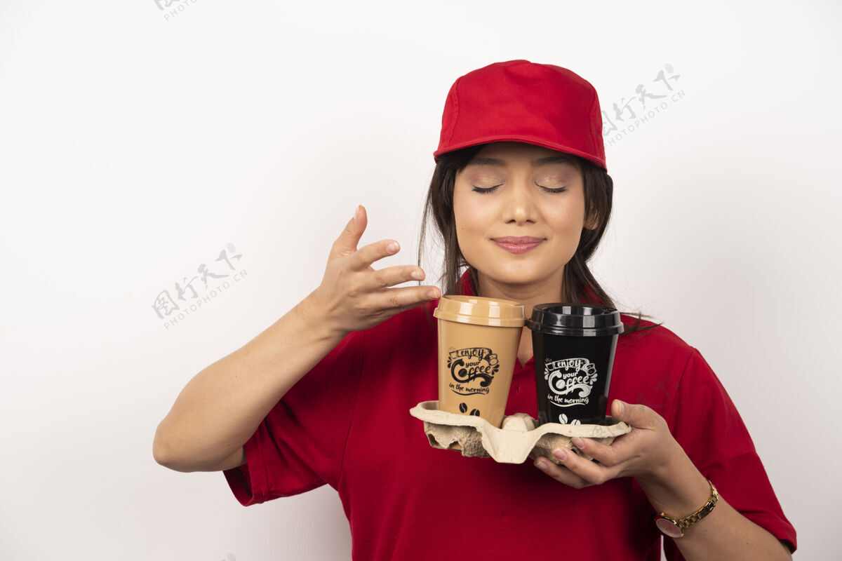 专业年轻的女快递员嗅着芳香的咖啡 在白色背景上送货快递人女士
