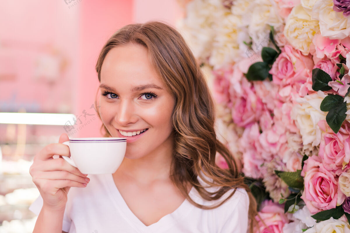 举行在咖啡厅喝咖啡的美丽微笑的女人在咖啡厅喝热茶的成熟女人的肖像喝咖啡的漂亮女人休息黑发杯子