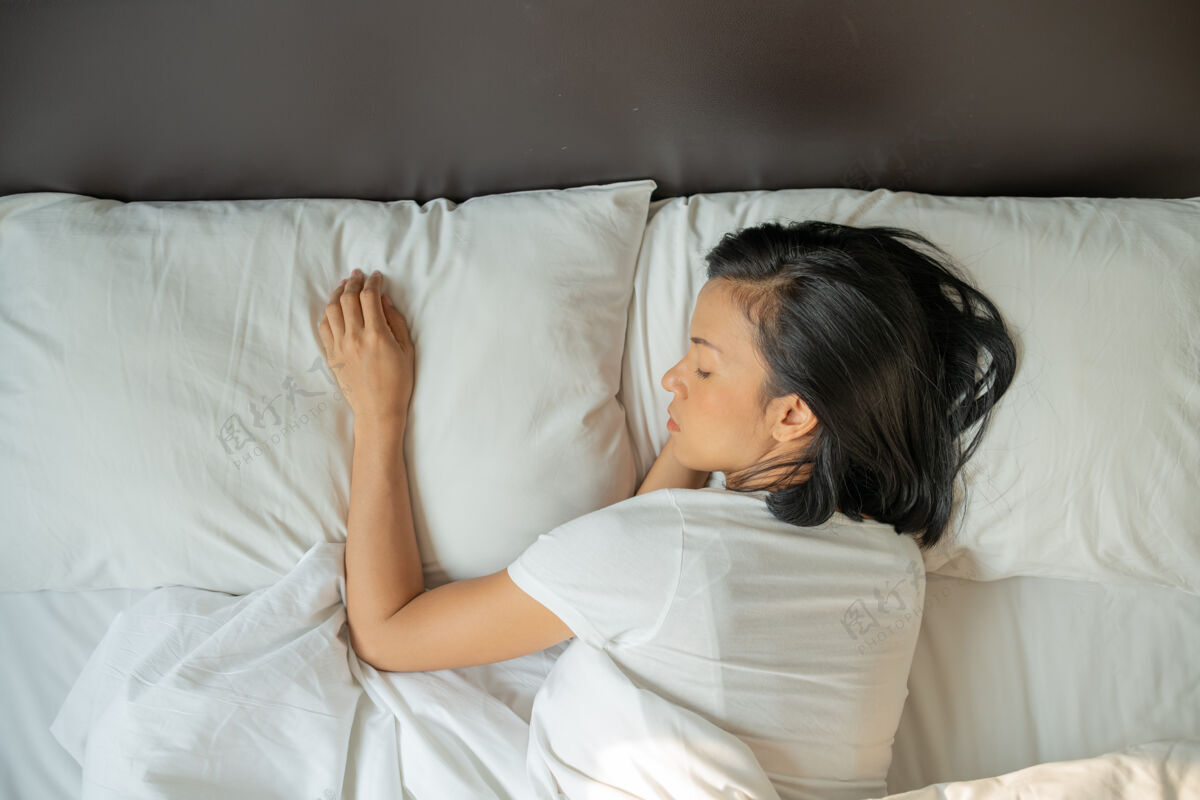 休息宁静的年轻女士穿着睡衣躺在床上睡着了顶视图躺下放松房间
