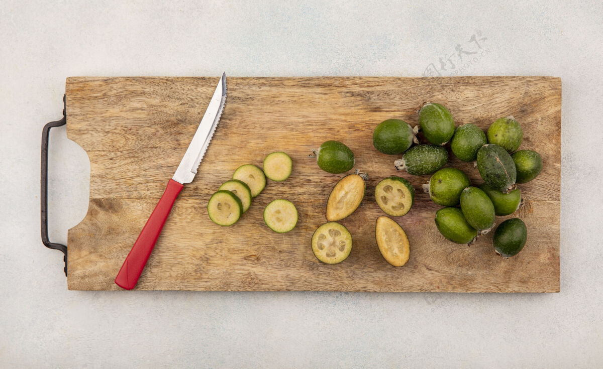 营养半个和整个新鲜的feijoas的顶视图被隔离在一个木制的厨房板上 刀子放在灰色的表面上饮食健康食物