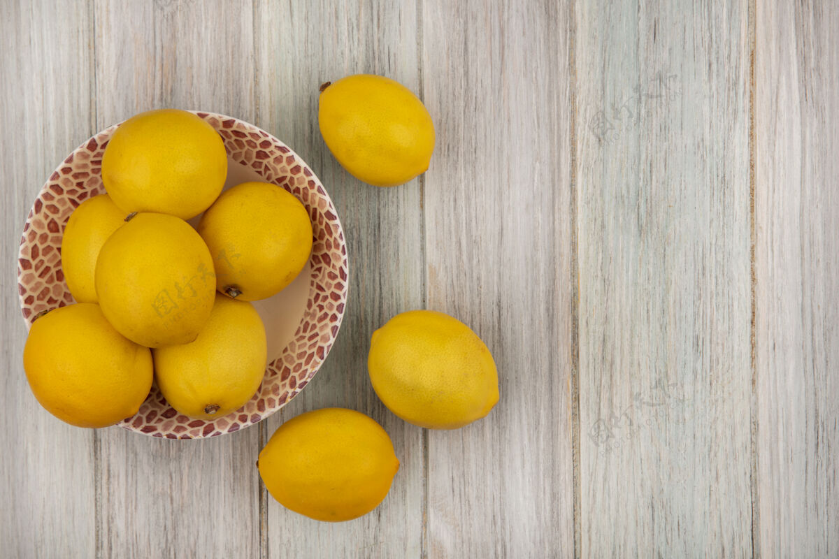 营养黄色皮肤的整个柠檬在一个碗的顶视图与柠檬隔离在一个灰色的木制表面与复制空间碗饮食块