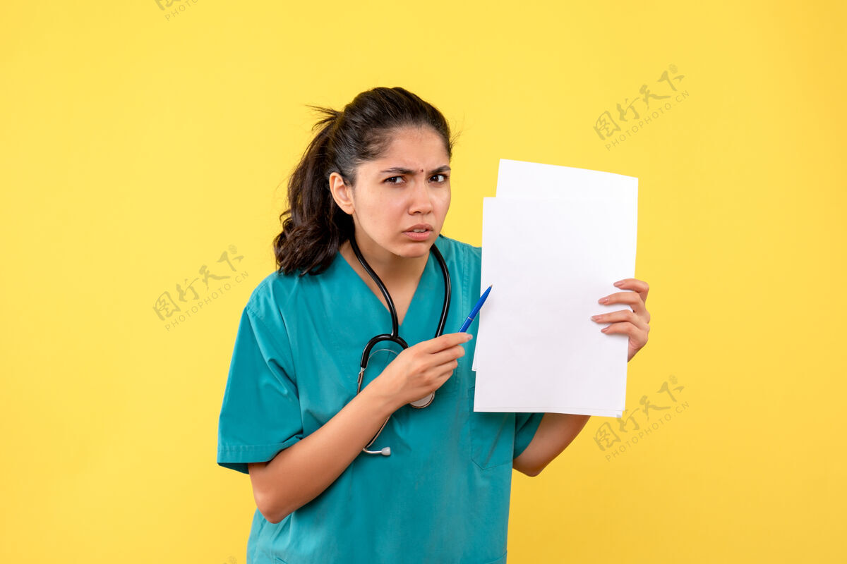 笔前视图困惑美丽的女医生拿着纸和笔在黄色的背景护理医生听诊器