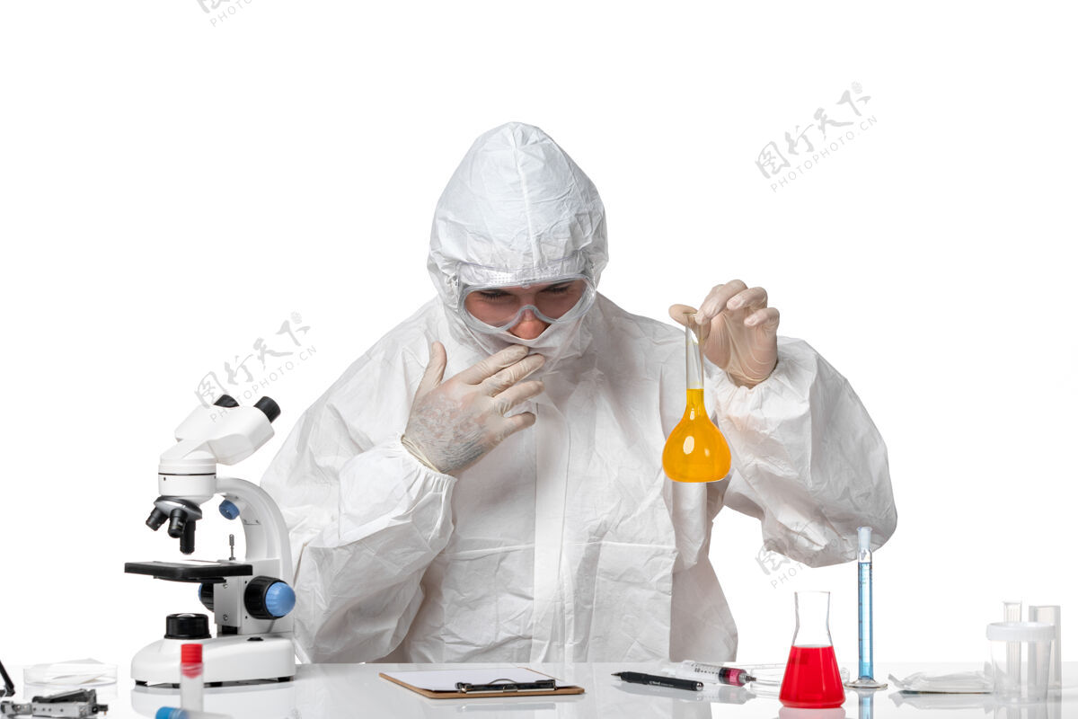 男性正面图穿着防护服的男医生拿着烧瓶 在空白处有黄色溶液药品病毒套装