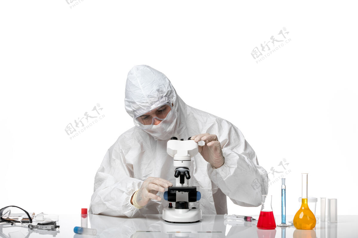 大流行前视图：男医生穿着防护服 戴着面罩 在空白处使用显微镜套装实验室外套专业