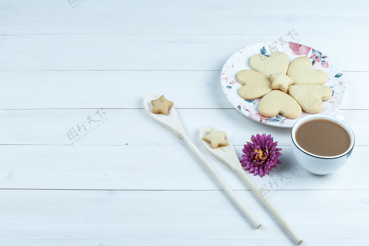 水平高角度观看心形饼干 一杯带花的咖啡 白色木板背景上的木勺星形饼干水平花高杯子