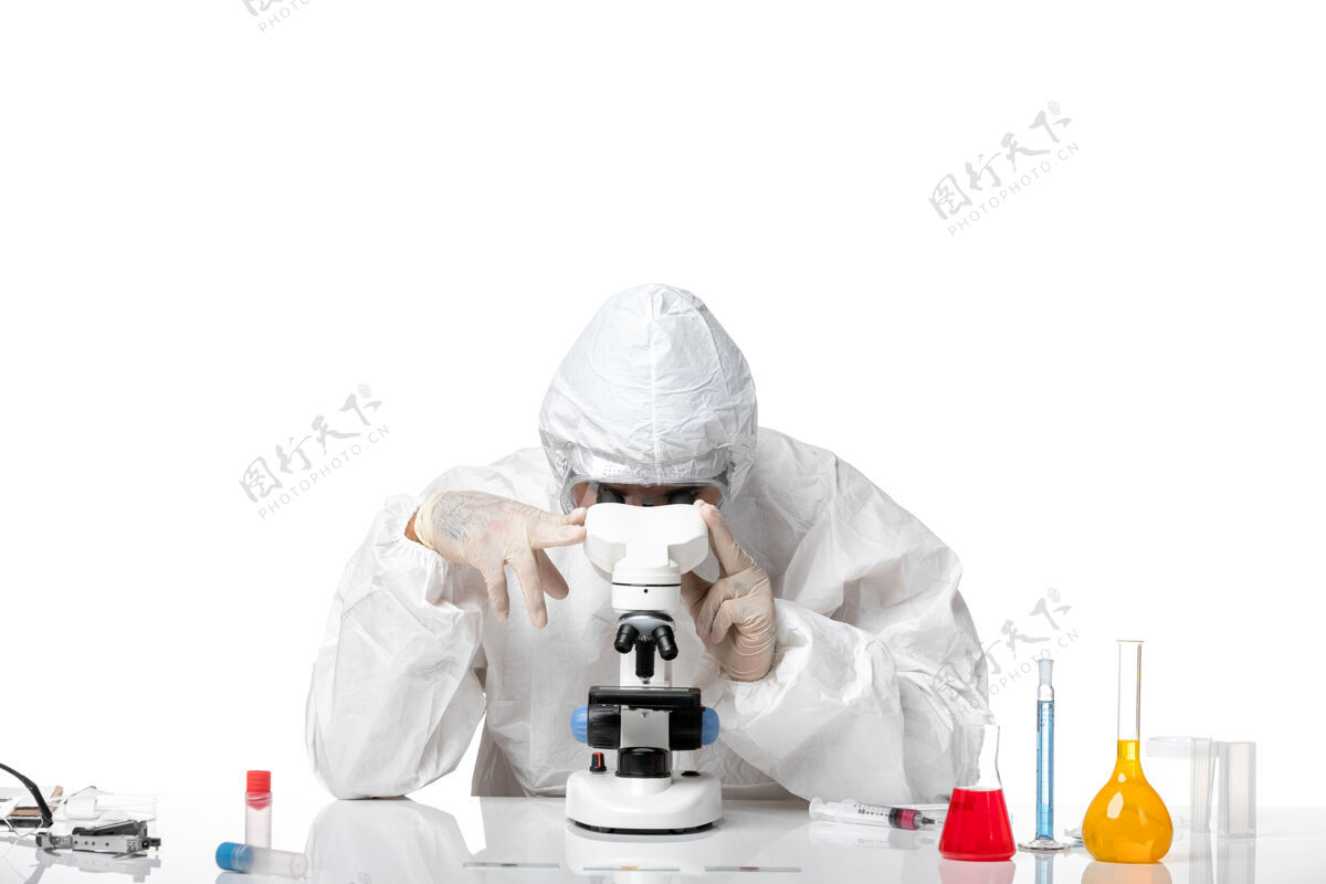 面具前视图：男医生穿着防护服 戴着面罩 在空白处使用显微镜实验室外套外套正面